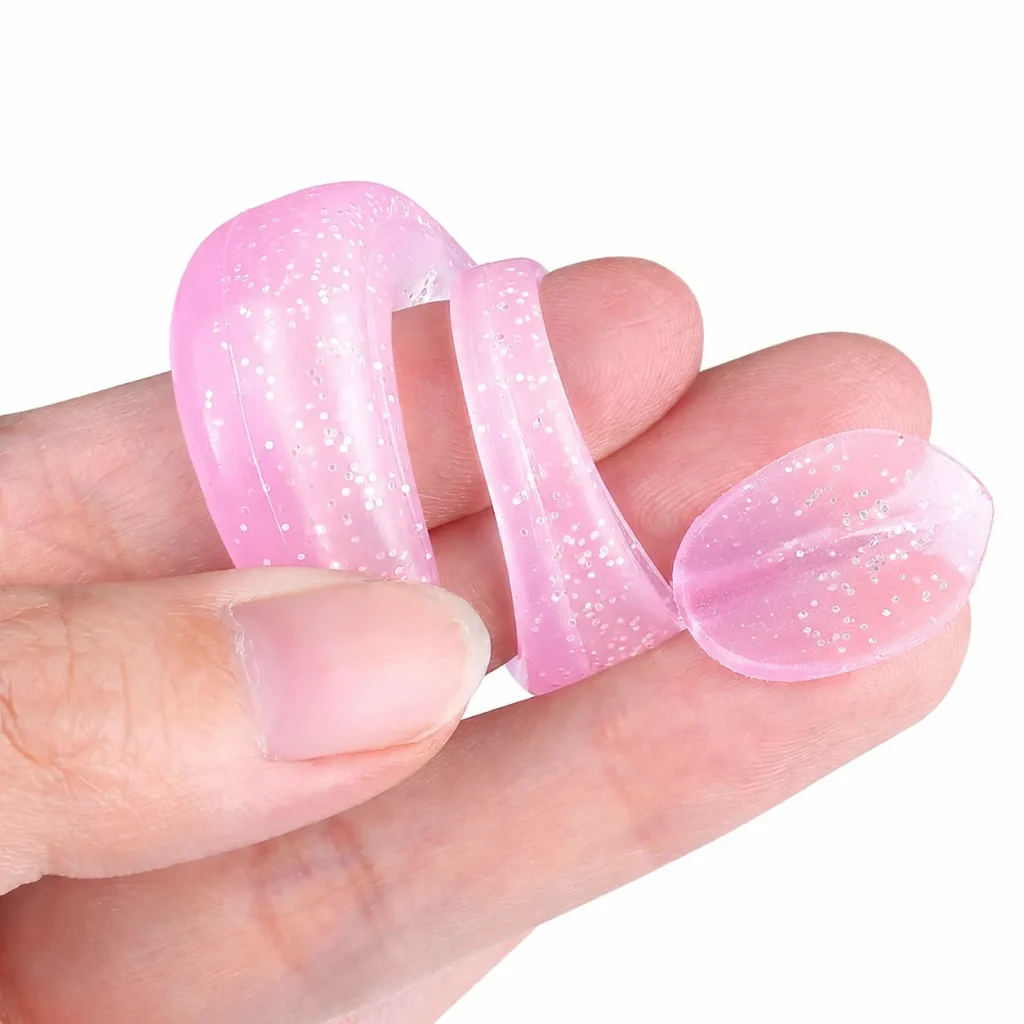 Pink silicone soft lure bent between fingers to show flexibility