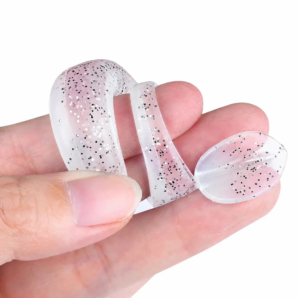 White glitter silicone soft bait bent between fingers to show flexible body