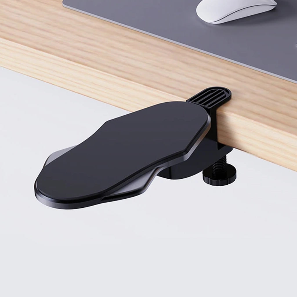 Black desk arm rest clamped to a wooden desk edge beside a computer mouse mat