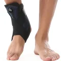 Black and blue ankle brace being worn with the cable adjustment dial visible