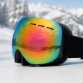 raindow tint snow goggles shown at an angle on snow with a black head strap