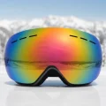 front view of rainbow lens snow goggles against a snowy mountain background